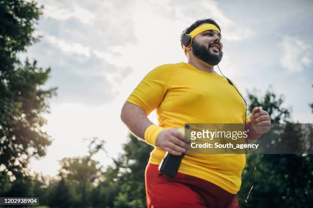 netter übergewichtiger mann joggt im park - fat guy running stock-fotos und bilder
