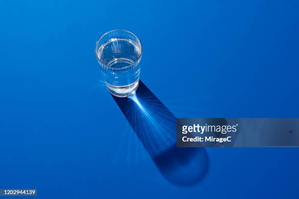 a glass of water on deep blue - glas stock-fotos und bilder