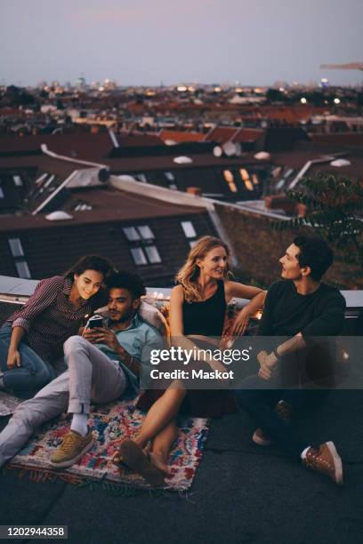 high angle view of friends relaxing together on terrace in city during rooftop party - berlin party stock pictures, royalty-free photos & images