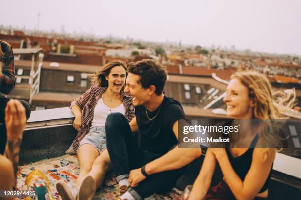 cheerful male and female friends enjoying on terrace during rooftop party - rooftop party stock pictures, royalty-free photos & images