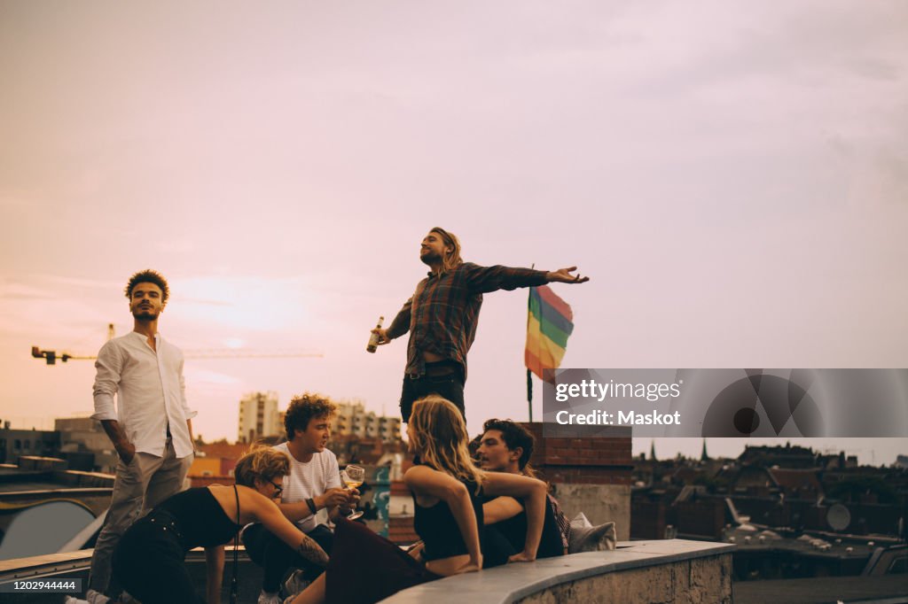 Man enjoying beer while relaxing with friends on terrace at rooftop party