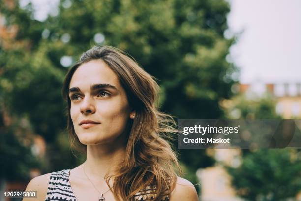 close-up of thoughtful young woman looking away in city - hazel eyes stock pictures, royalty-free photos & images