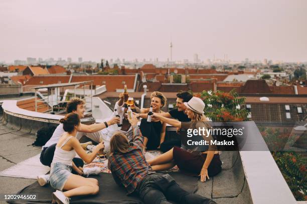 cheerful friends toasting beer while relaxing on terrace at city - beer cheers stock-fotos und bilder