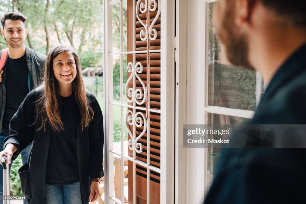 Midsection of male owner greeting guests at doorway of rental apartment