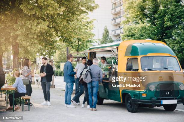 male and female customers standing by food truck - foodtruck stockfoto's en -beelden