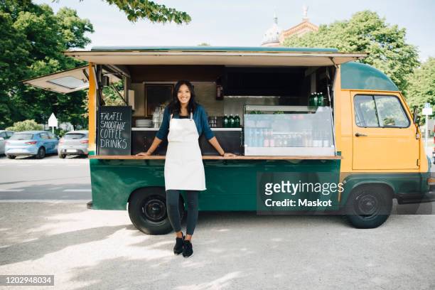 portrait of smiling female owner standing against food truck - foodtruck stockfoto's en -beelden