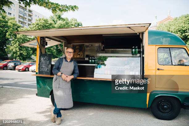 portrait of mature man standing against food truck - foodtruck stockfoto's en -beelden