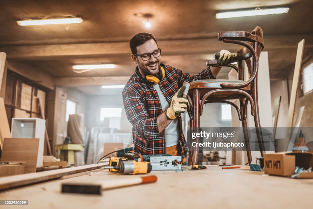 Männliche Möbel Designer sorgfältig Schleifen eines Stuhlrahmens
