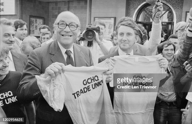 British Social Democratic Party politician Roy Jenkins and British Liberal Party politician David Steel pose holding up t-shirts in support of GCHQ...