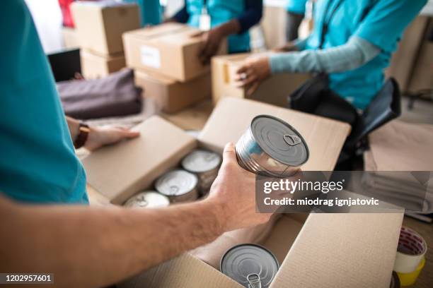 jonge mens die bij liefdadige stichting werkt, verpakkend schenkingsdoos - packing boxes stockfoto's en -beelden