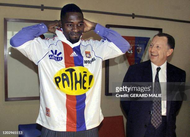 Le joueur de football Marc-Vivien Foe , milieu de terrain international camerounais, ajuste son nouveau maillot sous le regard du président de...