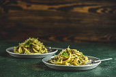 Spaghetti pasta bucatini with pesto sauce and parmesan. Italian traditional perciatelli pasta by genovese pesto sauce in two gray dishes