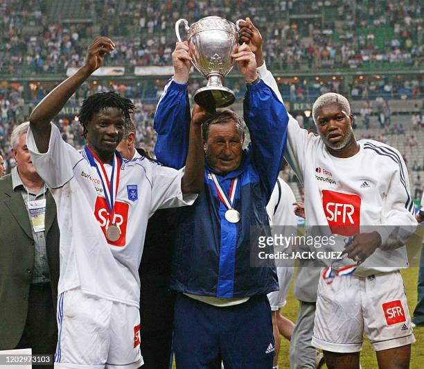 L'entraîneur d'Auxerre Guy Roux et ses joueurs l'attaquant zimbabwéen Mwaruwari Benjani et l'attaquant Djibril Cissé brandissent le trophée, le 31...