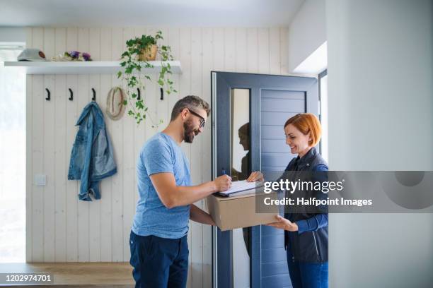woman courier and mature man signing for a parcel. - consegna a domicilio foto e immagini stock