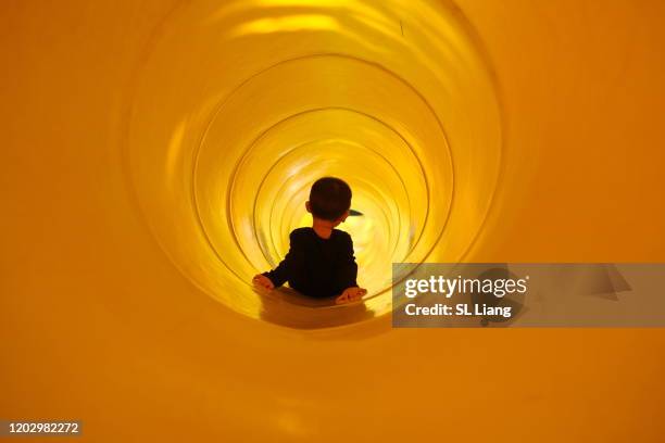 toddler boy playing slide in playground, taiwan - rutsche stock-fotos und bilder