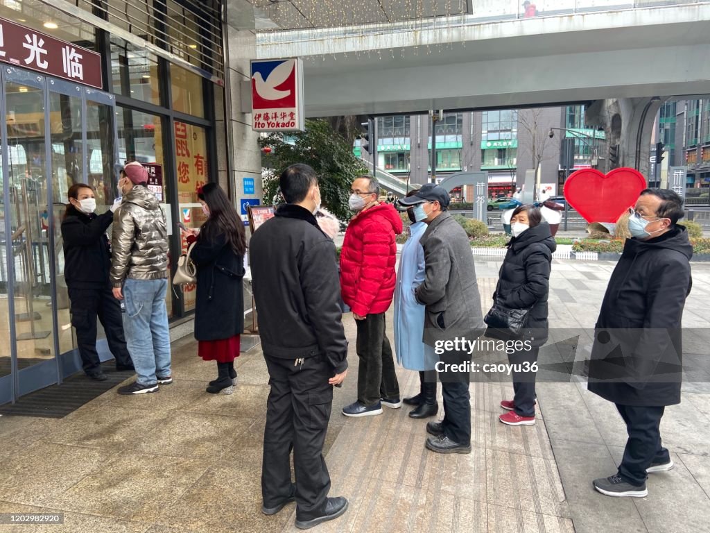 Wearing masks, people lined up for temperature checks before entering the mall in Chengdu,China