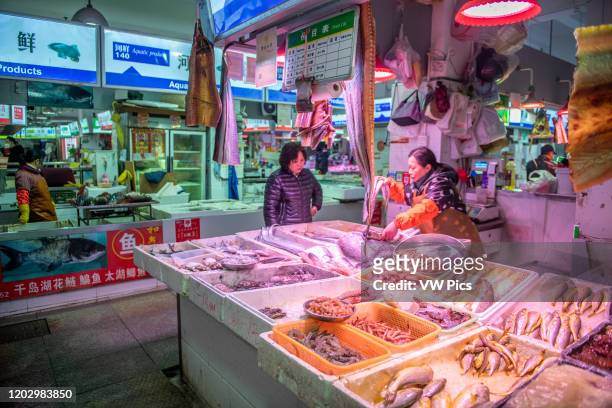 Shanghai, China, 26th Jan 2020, Woman store vendor shows various seafood option to woman at seafood market.