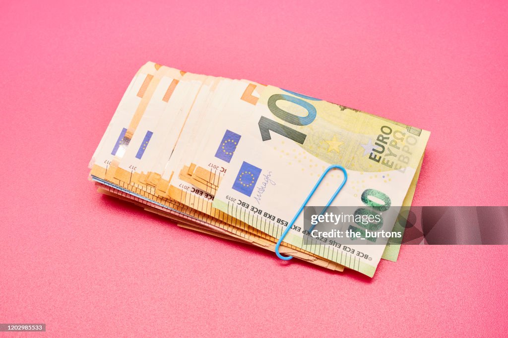 Directly above shot of a bundle of Euro bank notes on pink background