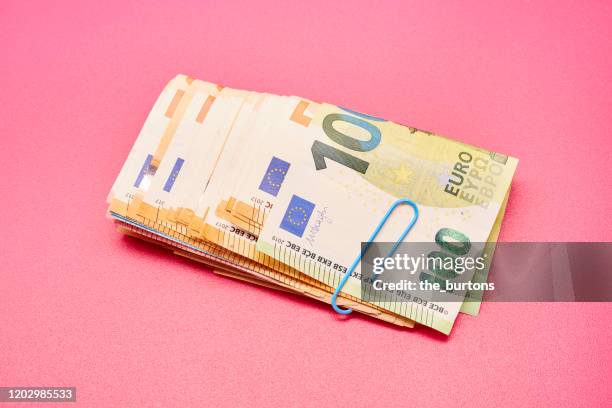 directly above shot of a bundle of euro bank notes on pink background - banknote stock-fotos und bilder