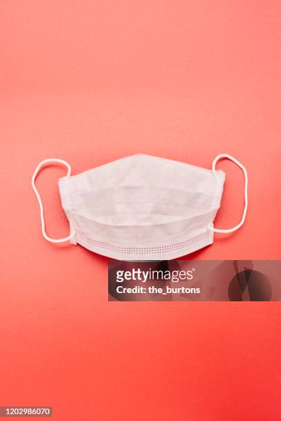 still life of a white face mask on red background - 風邪マスク ストックフォトと画像