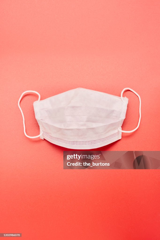 Still life of a white face mask on red background