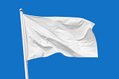 White flag waving in the wind on flagpole, isolated on blue background
