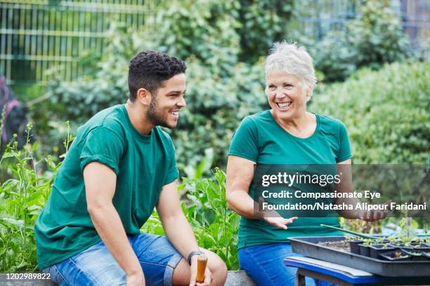 woman and man laughing in community garden - team t shirt imagens e fotografias de stock