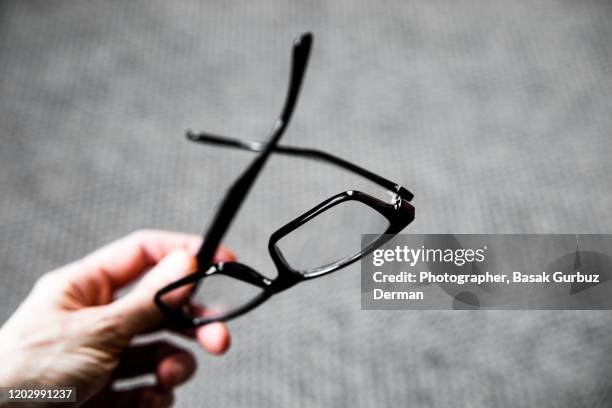 a hand holding reading glasses - leesbril stockfoto's en -beelden