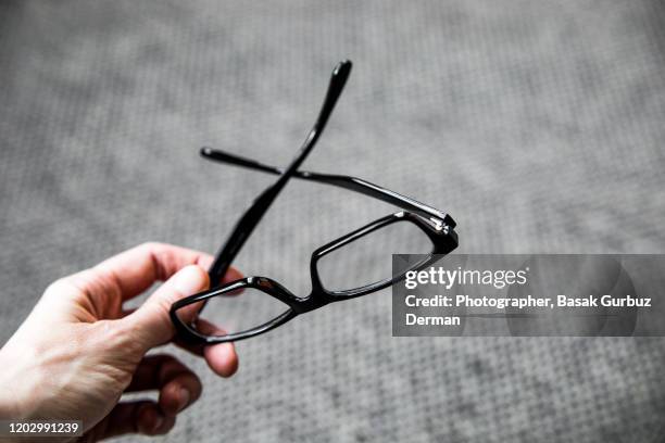 a hand holding reading glasses - lesebrille stock-fotos und bilder