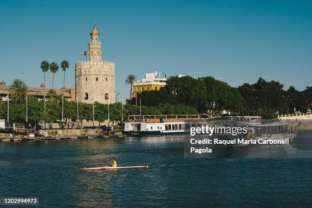 People canoeing in the Guadalquivir river with Torre del Oro in the background.