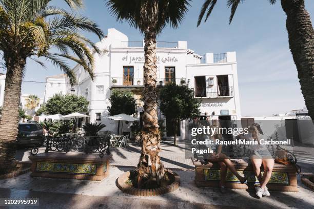 Two young tourists sit on a city bench in Spain square .