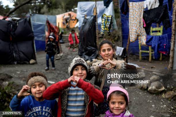 Children pose at the unofficial camp of the island of Samos on February 22, 2020. - For many of those who live on the Greek Aegean island of Samos it...