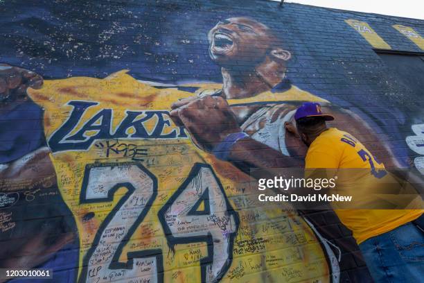 Fan writes a message on a mural for former Los Angeles Lakers basketball star Kobe Bryant during the official memorial ceremony for him and his...