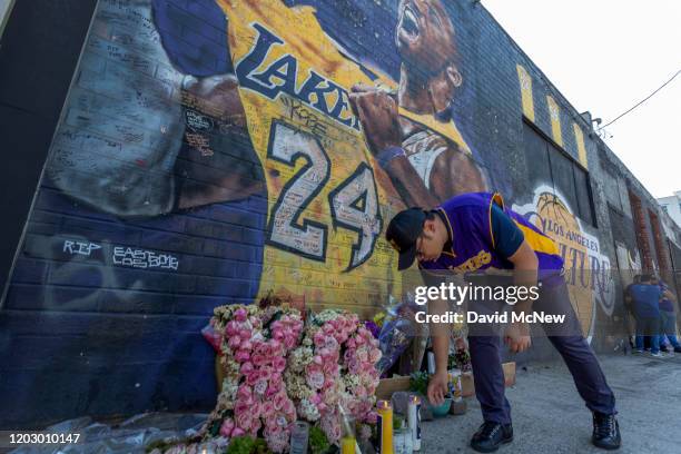 Man places a candle near a mural for former Los Angeles Lakers basketball star Kobe Bryant during the official memorial ceremony for him and his...