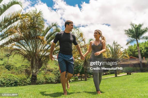 fitness couple walking across the lawn - side by side billboard stock pictures, royalty-free photos & images