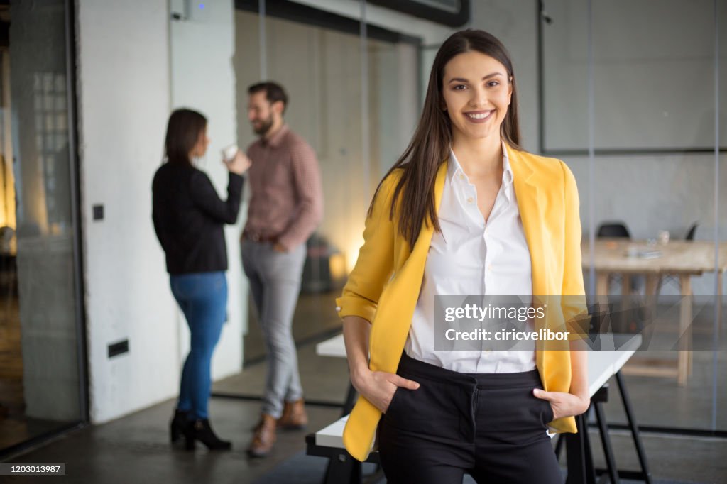 Mujer de negocios de moda de pie y mirando a la cámara