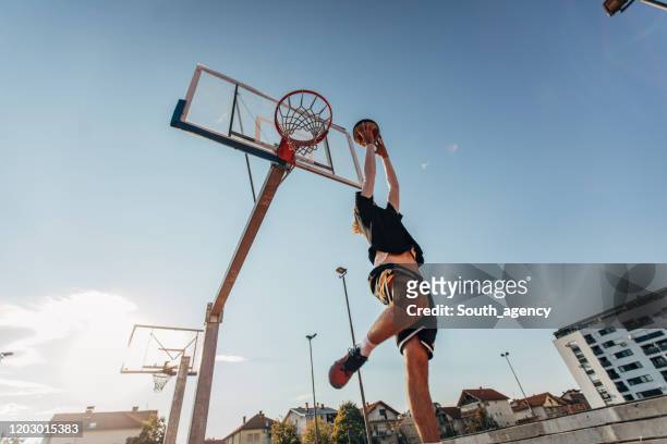 young man jumping and making a fantastic slam dunk - street games stock pictures, royalty-free photos & images