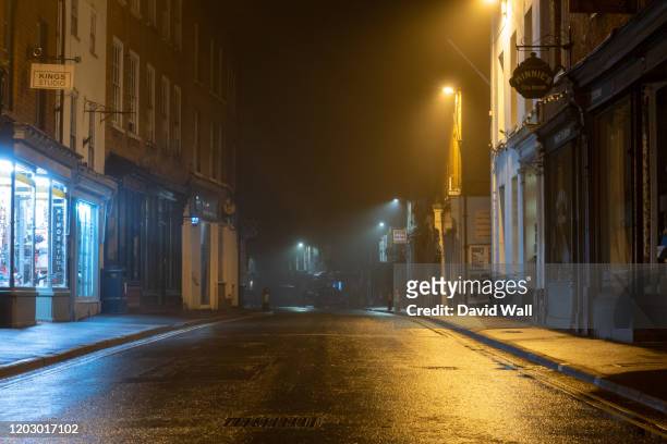 a wet high street with historic buildings with street lights glowing on a misty winters night. upton upon severn, uk - straat stockfoto's en -beelden