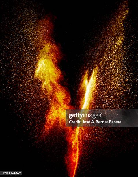 explosion by an impact of a cloud of particles of powder and smoke of color orange and yellow on a black background. - colourful studio shots stock-fotos und bilder