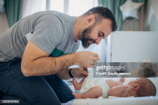 vater ändern baby sohn windel - changing diaper stock-fotos und bilder