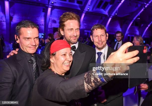 February 2020, Berlin: 70th Berlinale, Cinema for Peace Gala: Lawyer Seyran Ates photographs actor Gerard Butler and her bodyguards. Seyran Ates must...