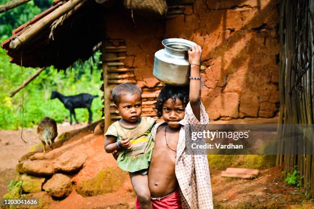 彼女の妹と彼女の頭の上に水を運ぶインドの小さな女の子 - child labor ストックフォトと画像