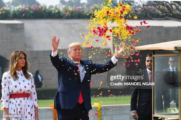 President Donald Trump sprays flower petals as First Lady Melania Trump looks on while paying their tribute at Raj Ghat, the memorial for Indian...