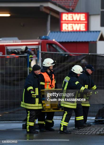 Firemen carry a generator at the site where a man who drove into a carnival procession, on February 25, 2020 in Volkmarsen near Kassel, central...