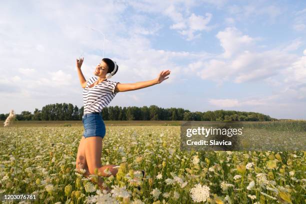 musique d'écoute de femme sur le pré d'été - casques découte sans fil photos et images de collection