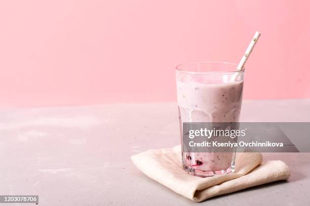 two glasses of blueberries smoothie on pink background. poring from blender into glass. - smoothie stock pictures, royalty-free photos & images