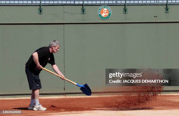 Un ouvrier prépare la terre battue d'un court de tennis le 09 avril 2010 au stade de Roland-Garros à Paris. Le tournoi de tennis de Roland Garros se...