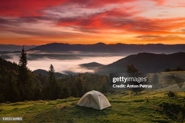 tent at sunrise on the background of the misty mountains - camping fotografías e imágenes de stock