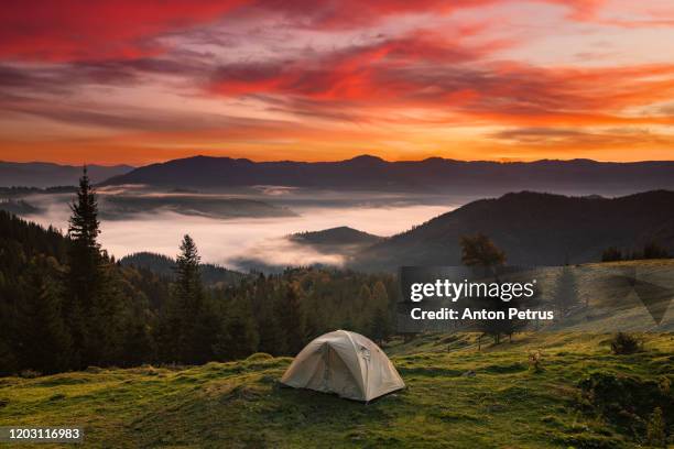 tent at sunrise on the background of the misty mountains - meadow stock photos et images de collection