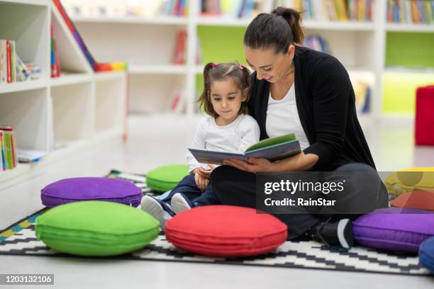 mother and daughter are reading books in the nursery - library kids stock pictures, royalty-free photos & images